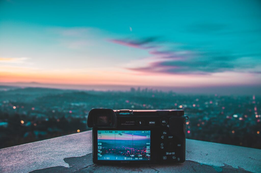 Camera capturing a stunning cityscape and colorful sunset from a high vantage point.